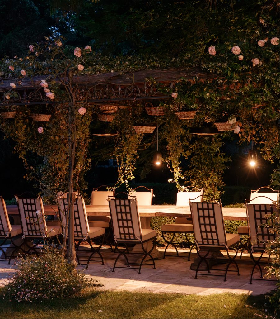 Dîner nocturne sous une pergola fleurie, mobilier de jardin en fer forgé Hervé Baume collection HB1 Quadrillage