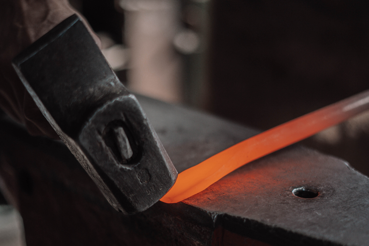 Hot-forging iron by hand with a hammer, part of the traditional craftsmanship behind Hervé Baume furniture.